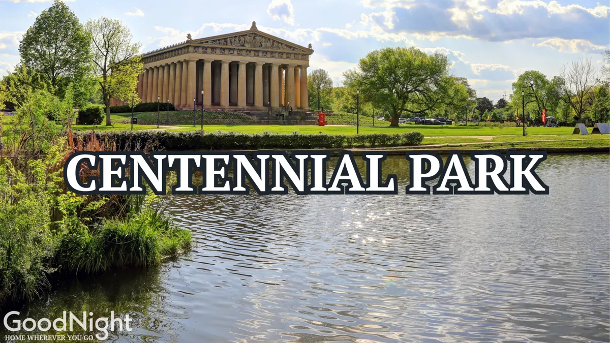 An exterior shot of a Parthenon-like structure surrounded by tranquil water and lush greenery. The setting suggests a spacious city park ideal for picnicking, walking, or enjoying cultural events, with people relaxing by the water and open green spaces inviting outdoor activity.