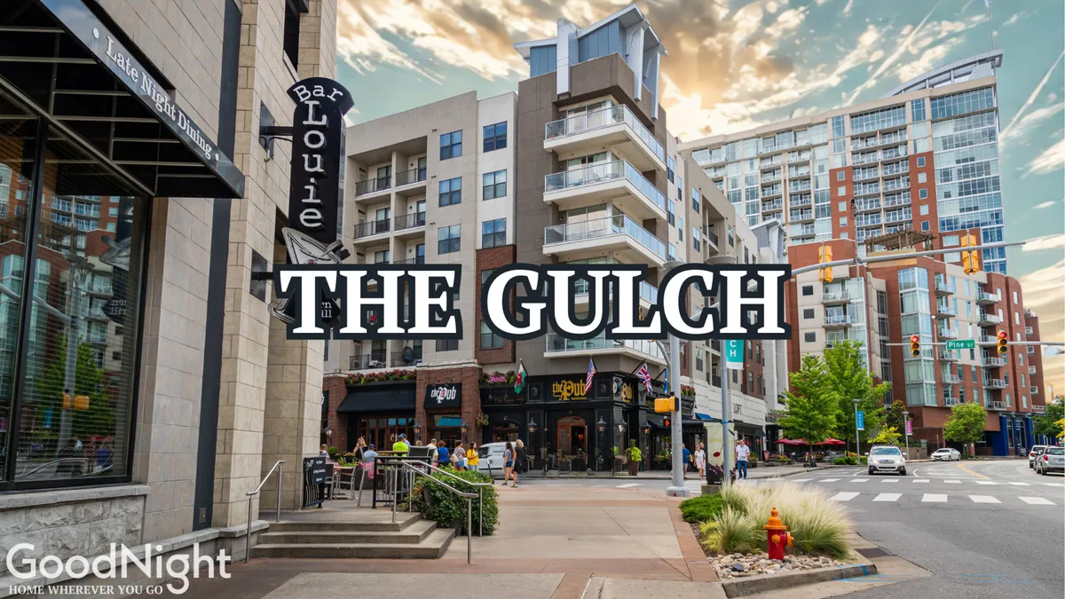 A lively city street scene featuring Bar Louie in the foreground, flanked by modern apartment buildings and bustling with pedestrian activity. Street signs and visible storefronts hint at the vibrant dining and nightlife options in the area, while people are seen enjoying outdoor urban life.
