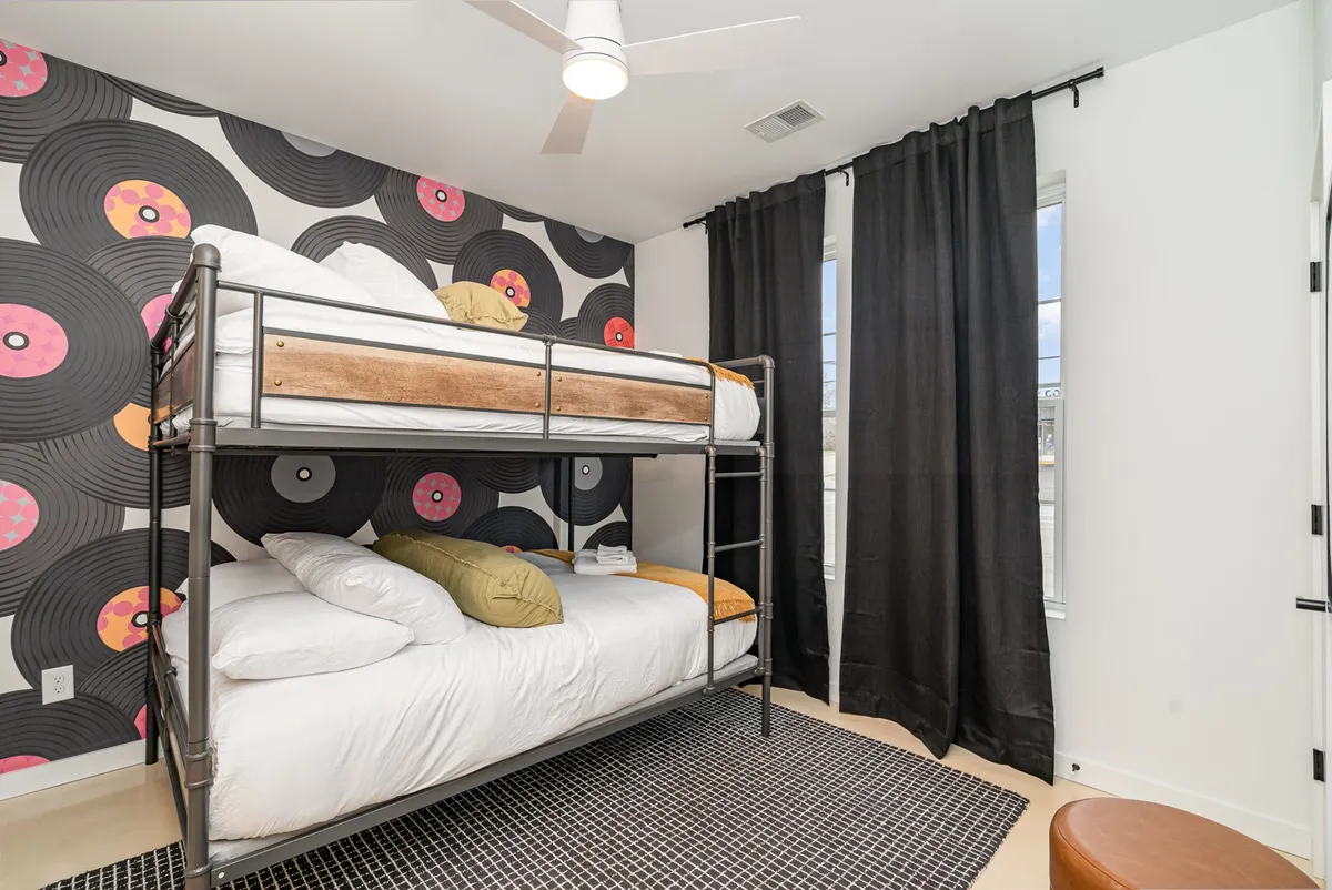 A playful bunk room featuring built-in bunk beds, vinyl record wallpaper, and black curtains. The room feels fun and relaxed, ideal for group stays or kids’ slumber parties.